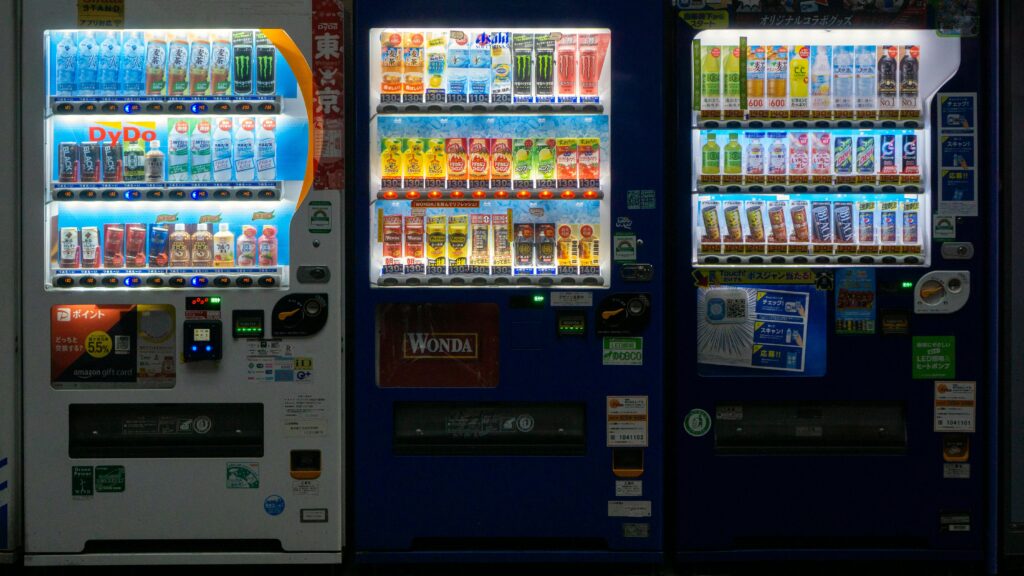 Three vending machines in Taito City, Tokyo at night showcasing a variety of drinks.